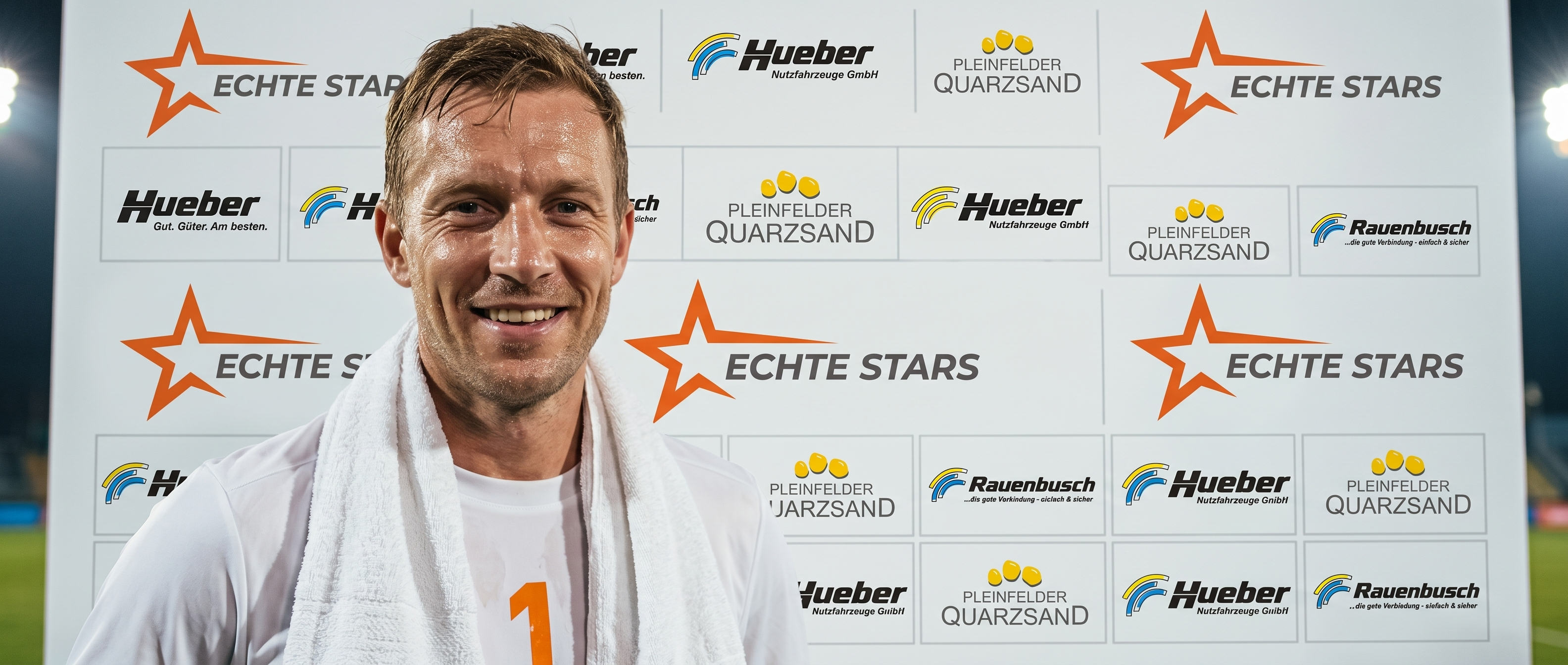Spieler lächelt frontal vor der Sponsorenwand